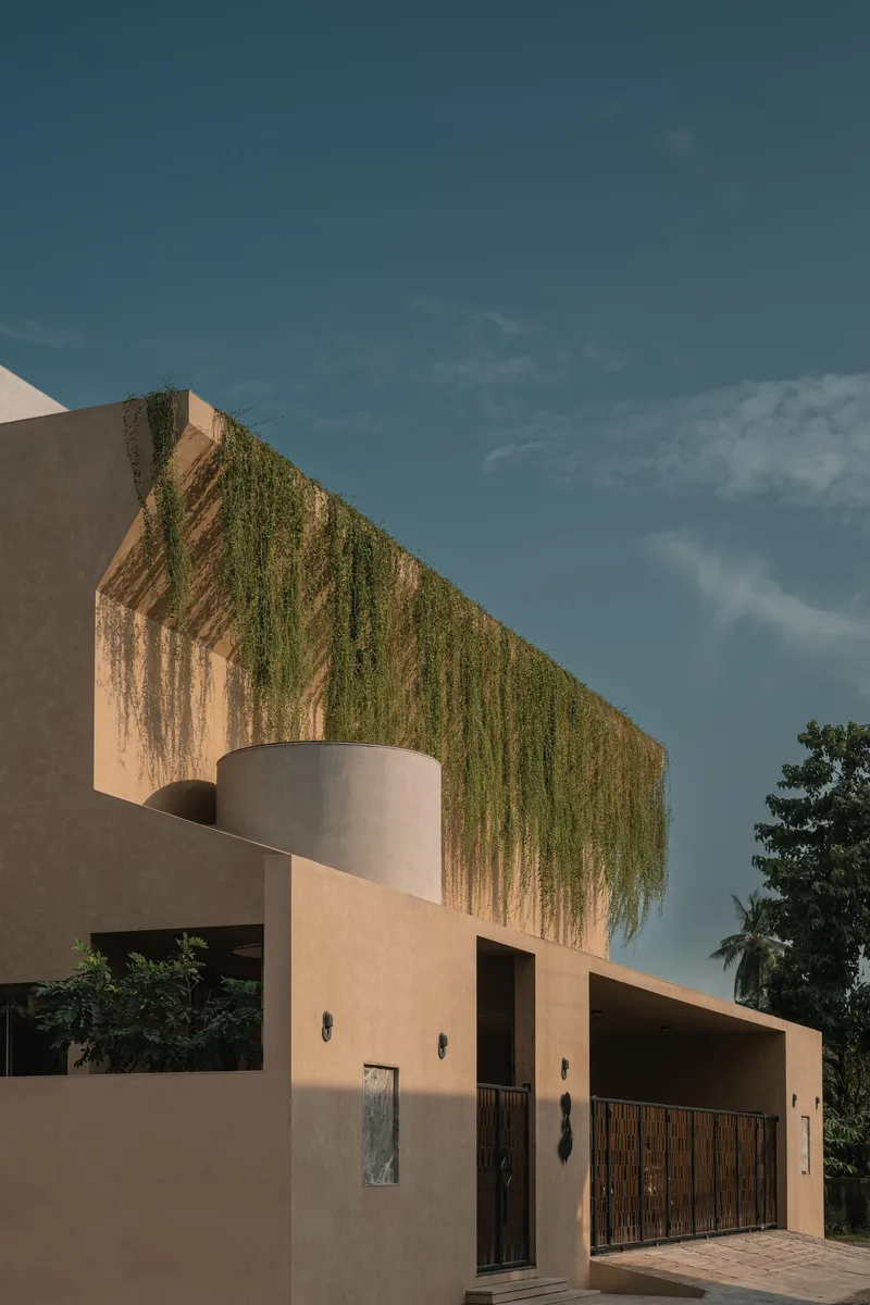 Street facade showing a cylindrical volume and trailing vines against dramatic clouds