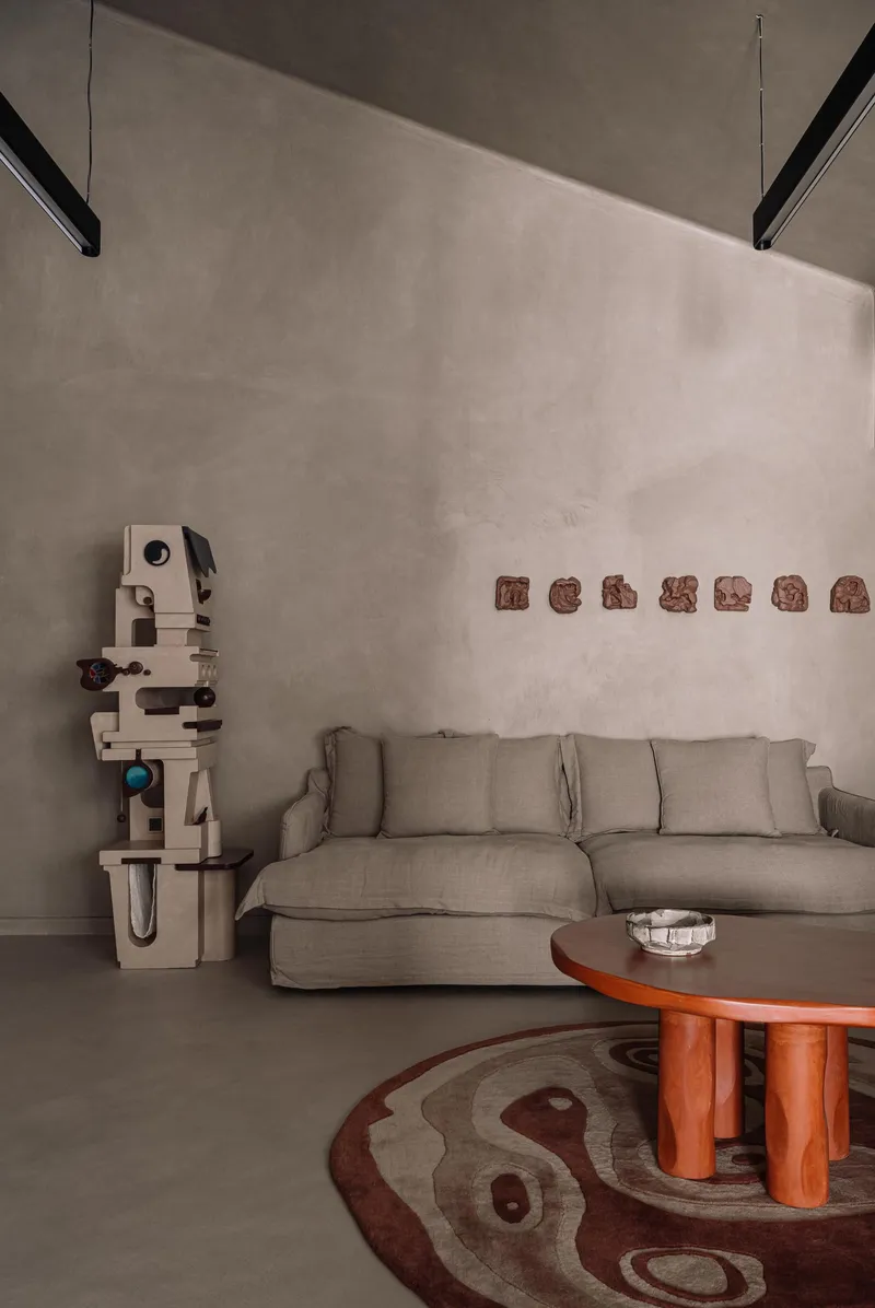 Living room with poured concrete walls, a beige sectional sofa and linear pendant lights above