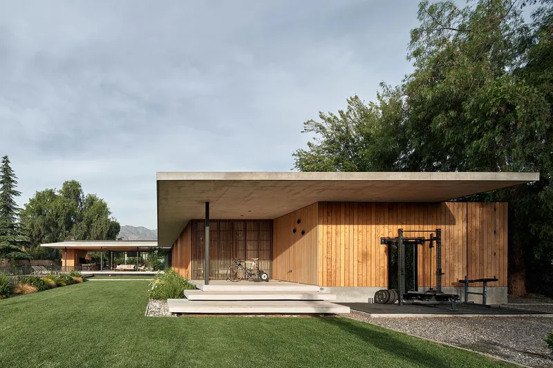 Garden facade with timber deck steps leading to vertical slat screens and an outdoor gym area