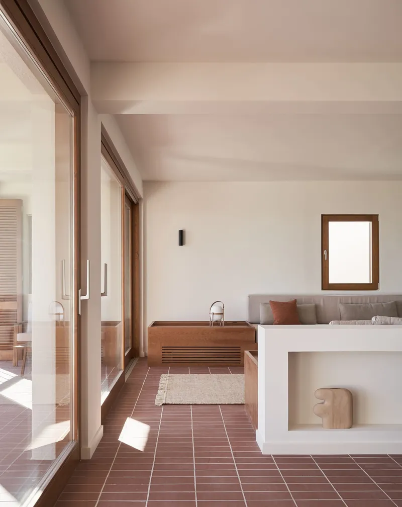 Interior hall with terracotta tile floor and timber kitchen unit bathed in afternoon sunlight