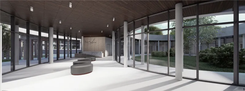 Interior lobby with cylindrical seating element, white columns, and full-height glazing overlooking courtyard gardens