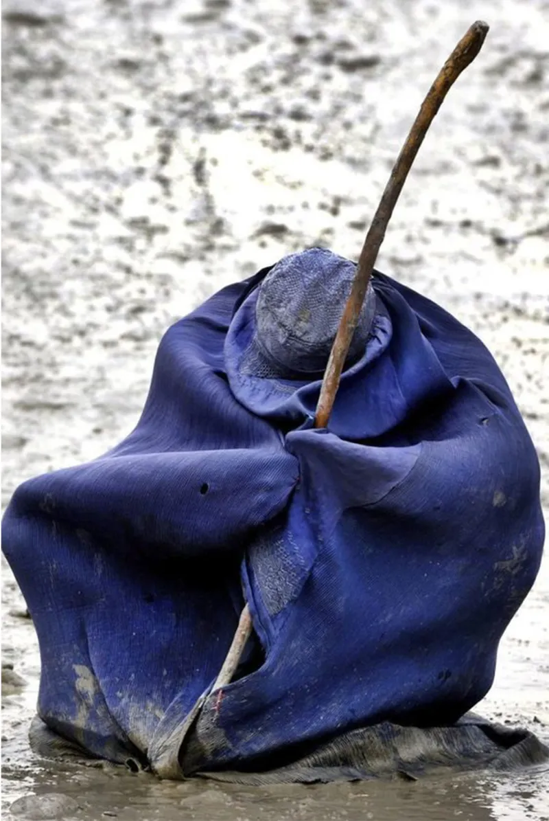 A blue cloak captures hardship, endurance, and silent resilience.