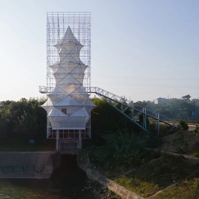The scaffolded pagoda-like structure with its ramped bridge crossing a canal at dawn