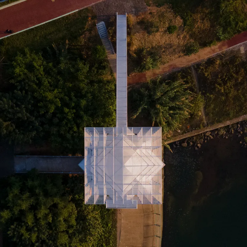 Overhead drone view of the pyramidal roof platform and metal walkway surrounded by dense trees and red pathways
