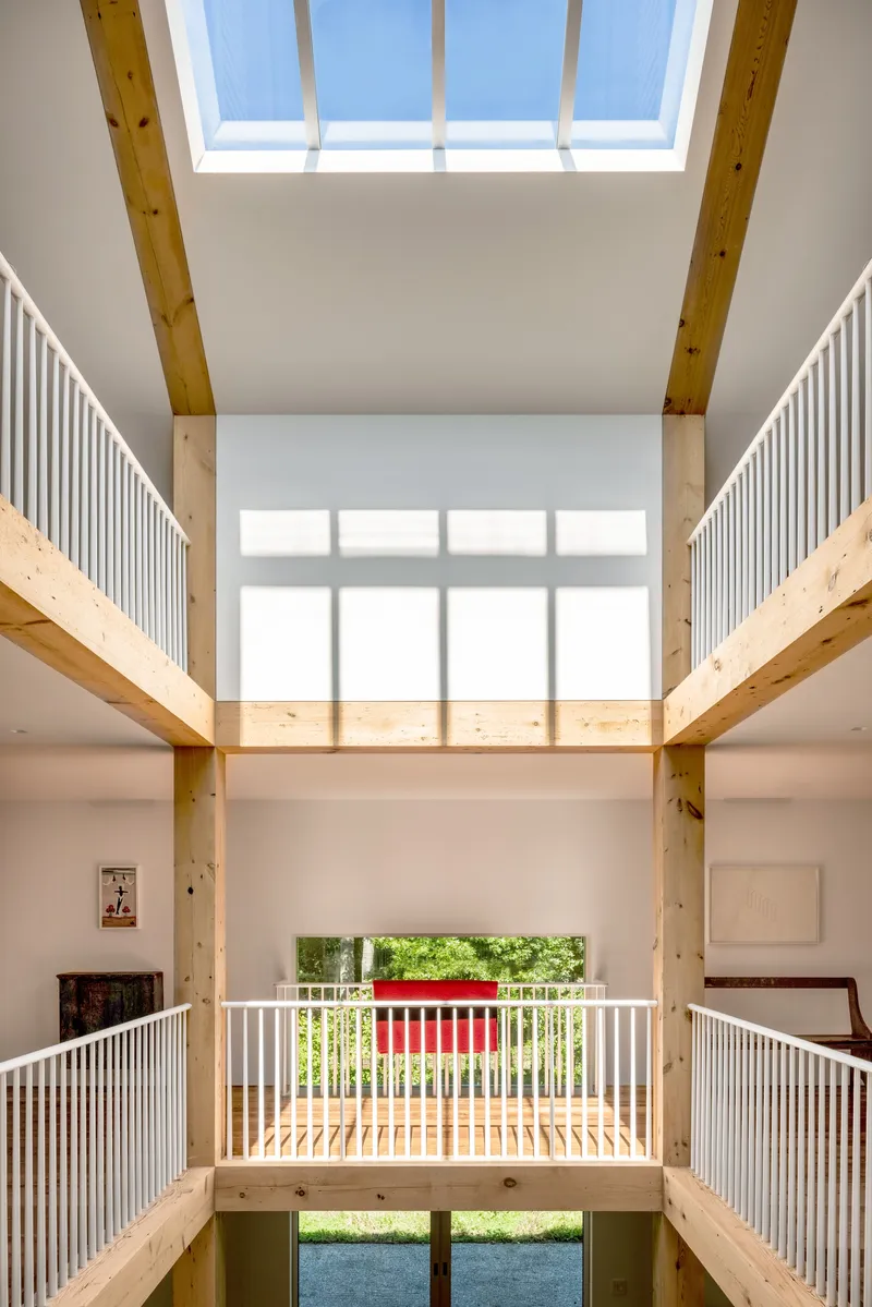 Central atrium with layered timber balconies and rectangular skylight framing the ceiling