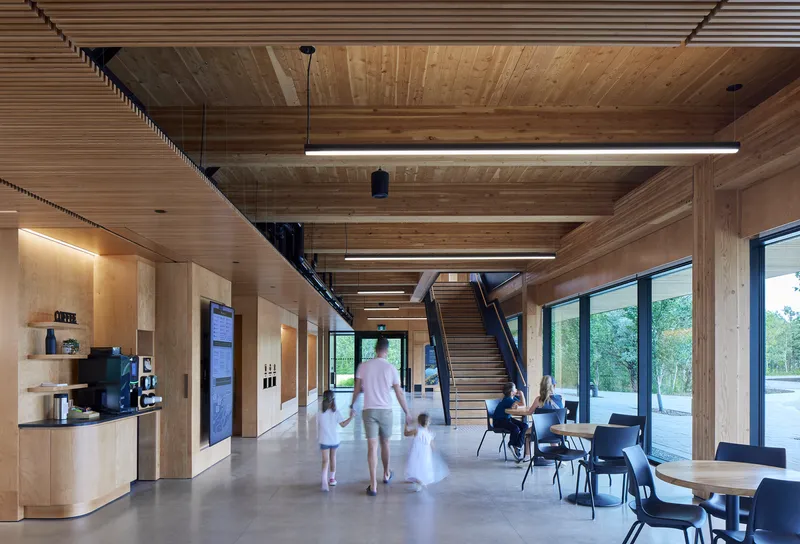 Lobby with exposed timber ceiling beams, steel staircase, and family walking through the space