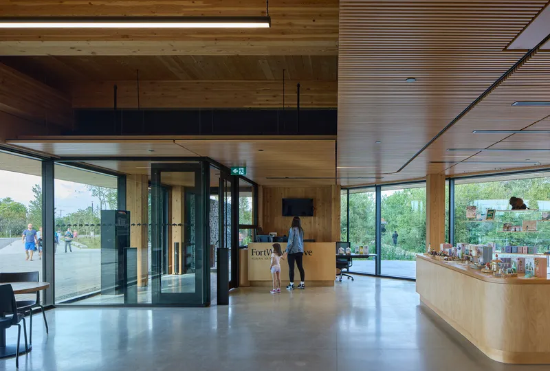 Entrance lobby with timber-clad ceiling and floor-to-ceiling glazing opening to parkland beyond