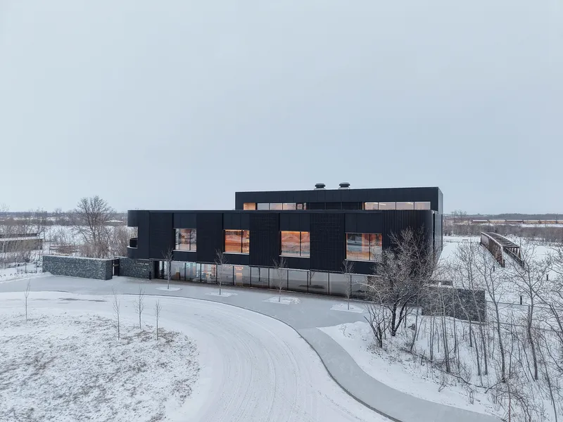 Aerial view showing the black corrugated envelope and curved access drive in a snowy landscape