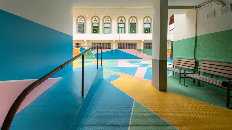 Covered walkway alongside the pastel geometric courtyard pavement with wooden bench on green painted wall