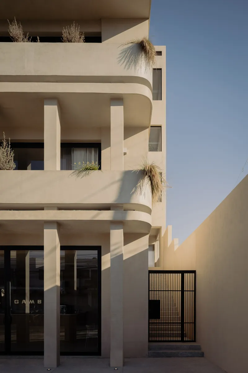 Close-up of stacked curved balconies with columns and grasses in the afternoon sun