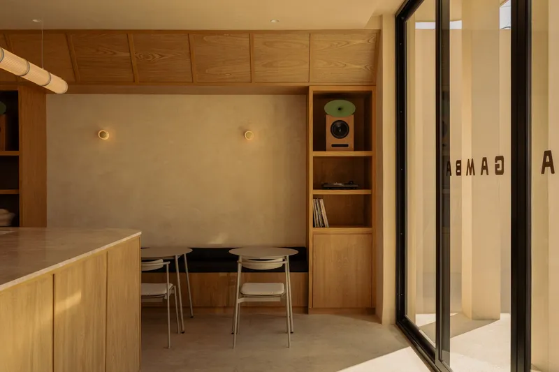 Dining nook with timber ceiling and built-in shelving beneath warm wall sconces