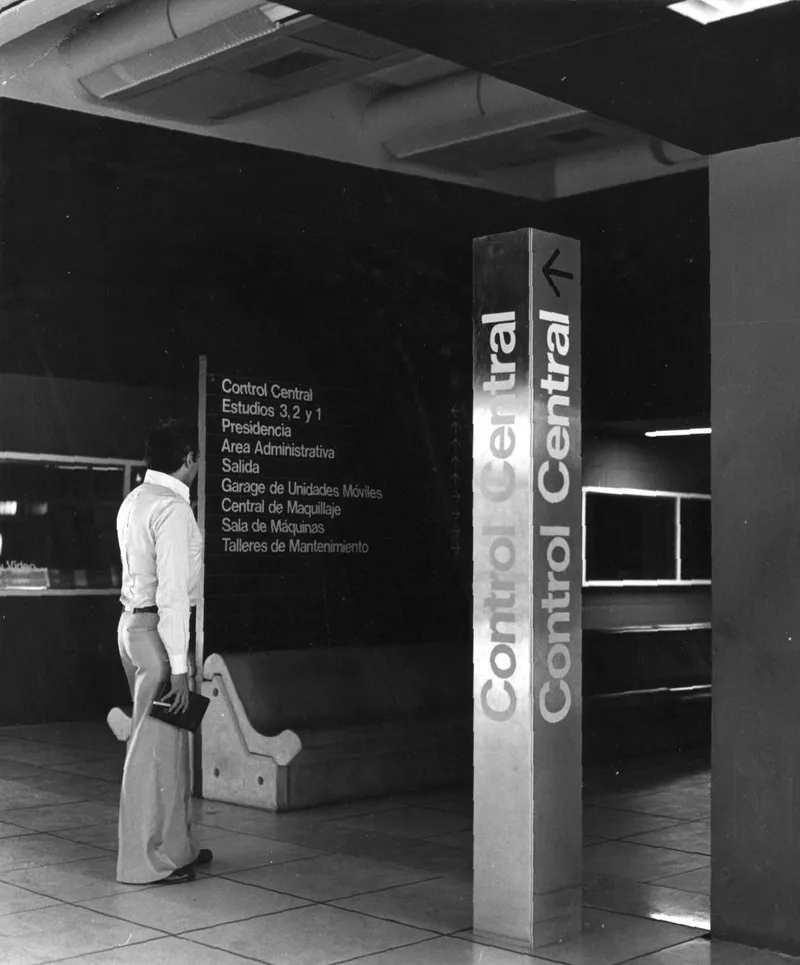 Interior lobby with freestanding directional signage column and visitor carrying a briefcase