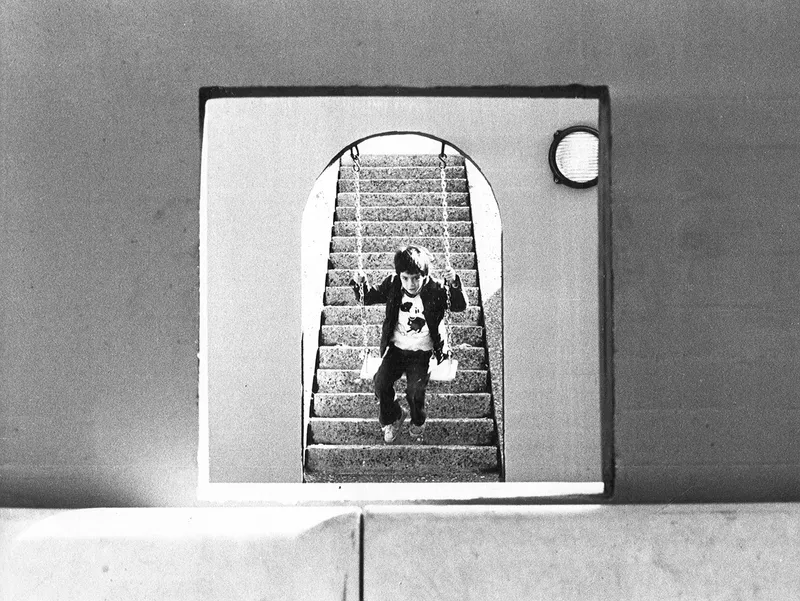 Arched doorway with circular window framing a view of stone steps and a figure descending
