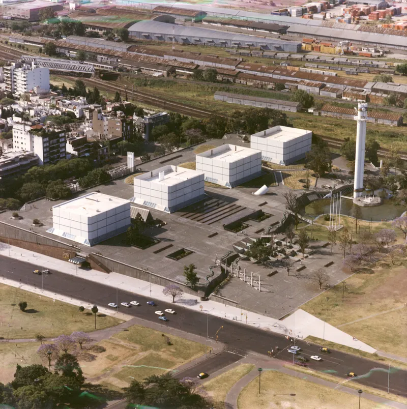 Aerial view of white cubic volumes arranged around a plaza with a cylindrical tower