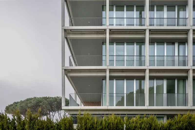 Detail of stacked balconies with metal railings, deep overhangs and glass doors on an overcast day