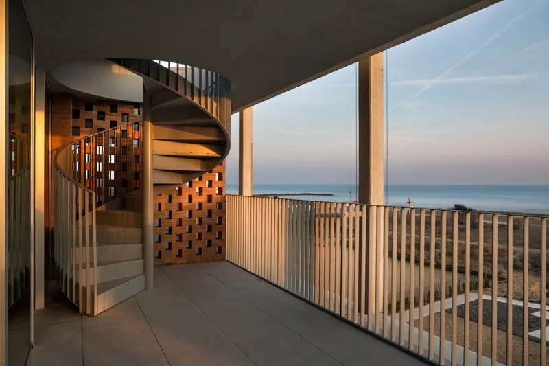 Covered terrace with spiral stair, timber slatted screen and ocean horizon at sunset