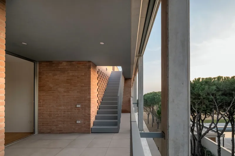 Covered terrace with exposed brick walls and a concrete staircase leading to the upper level