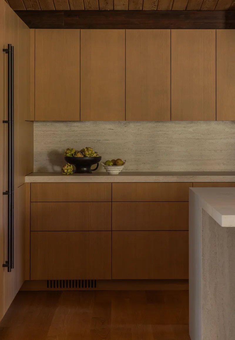 Kitchen counter with horizontal stone slab backsplash and timber cabinetry under wood ceiling