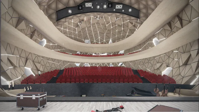 Auditorium interior with red tiered seating and geometric ceiling with suspended lighting rig