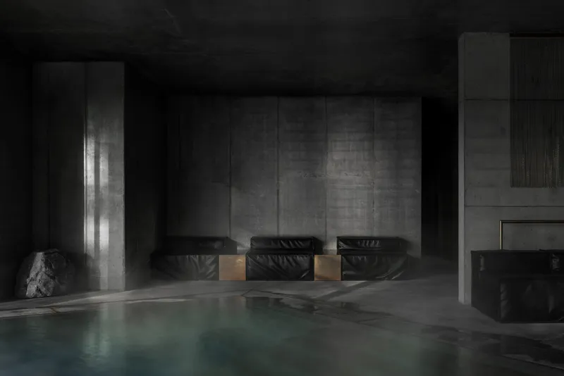 Three black leather lounge chairs against concrete wall beside pool edge with dramatic side lighting