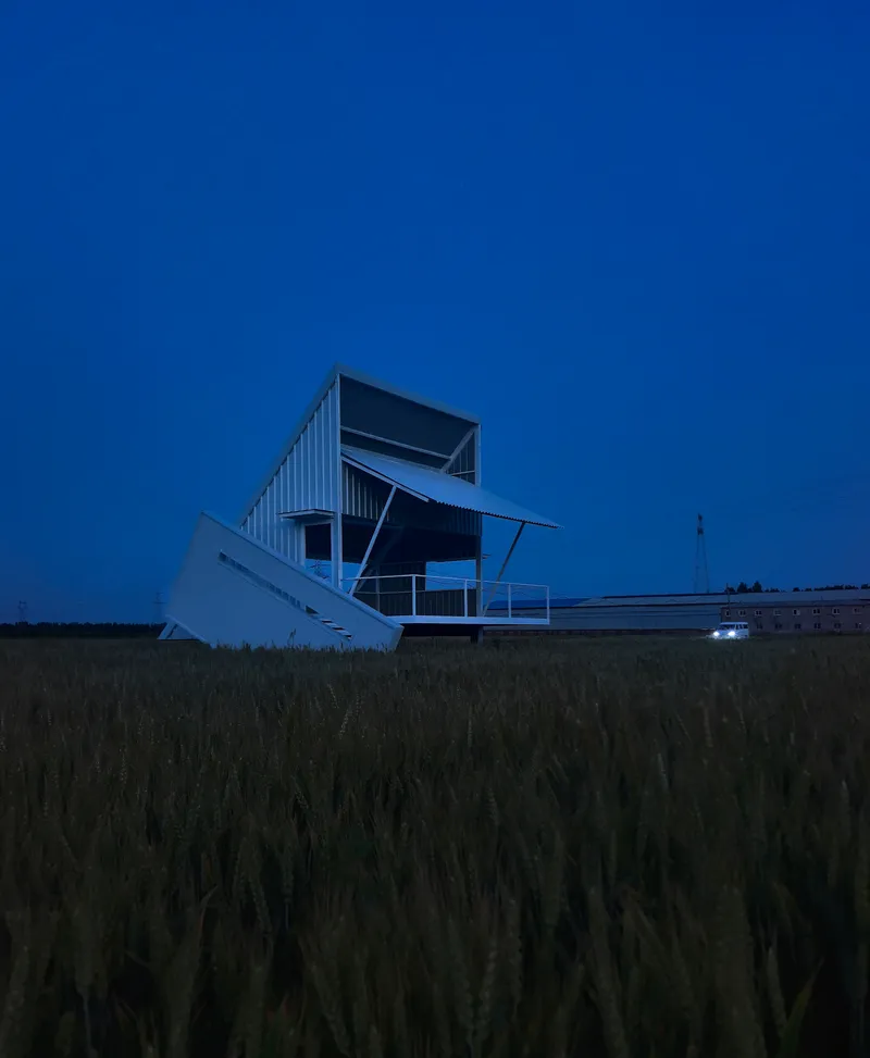 Metal observation structure with angled staircase and platform silhouetted against deep blue twilight sky