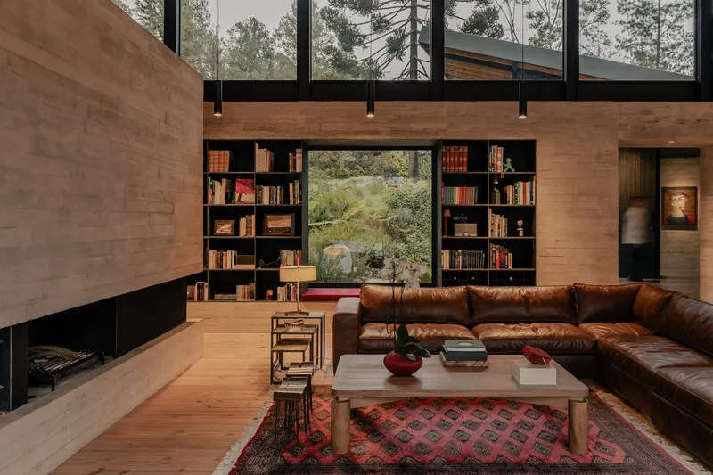 Built-in bookshelf flanking a window seat with views to the forested landscape outside