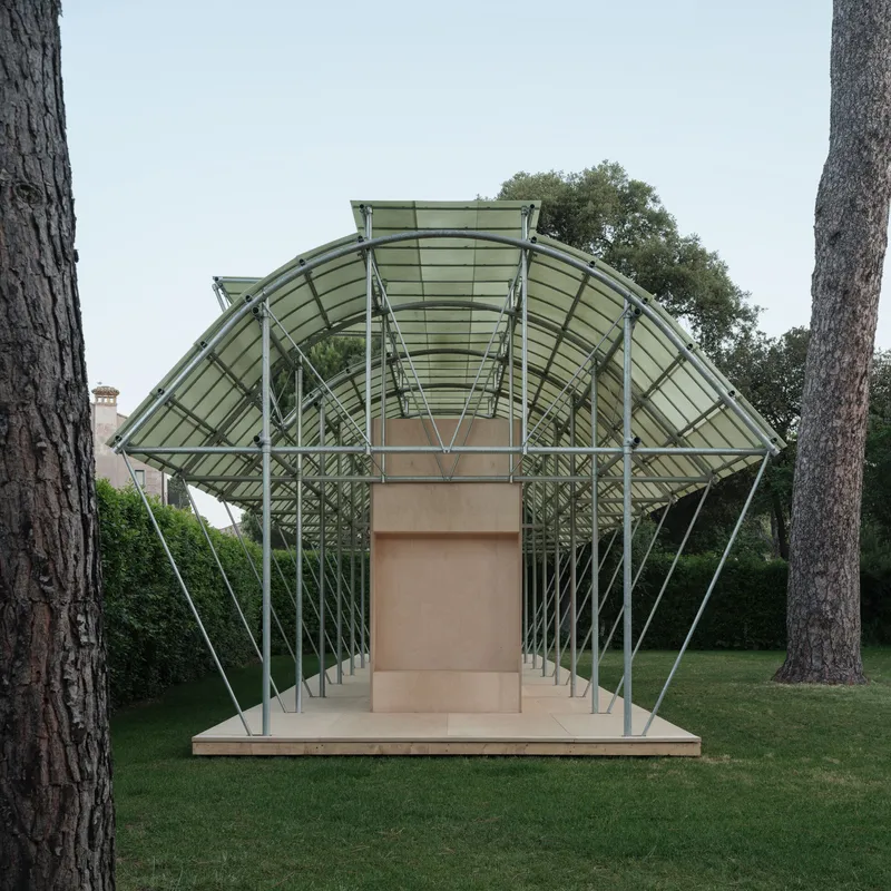 Head-on view of the arched steel structure with glass panels rising above the timber service core