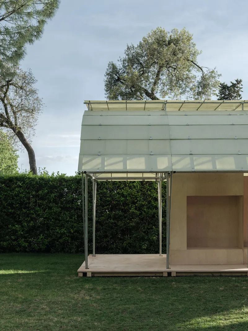Side view of the pavilion showing timber deck, diagonal steel supports, and plywood enclosed volume