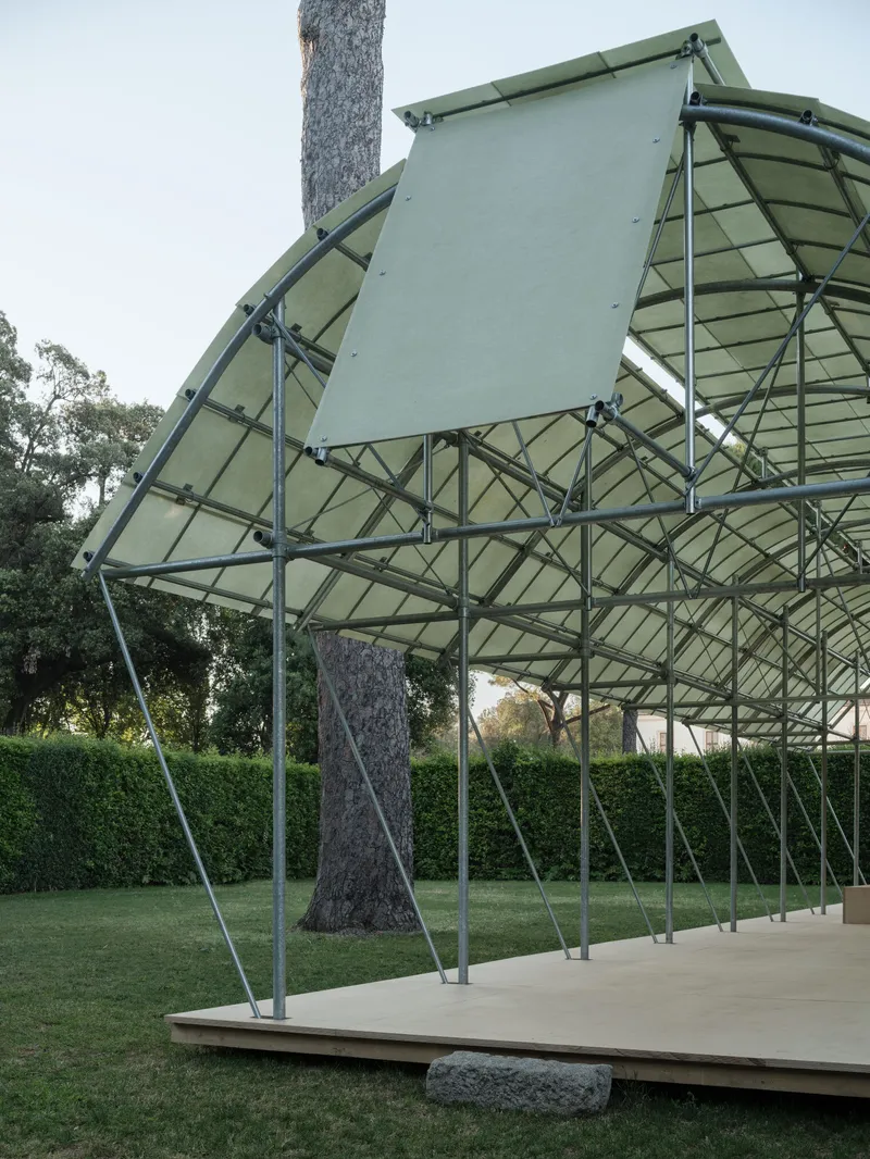 Underside of the angled roof structure showing steel lattice and translucent panels around a tree