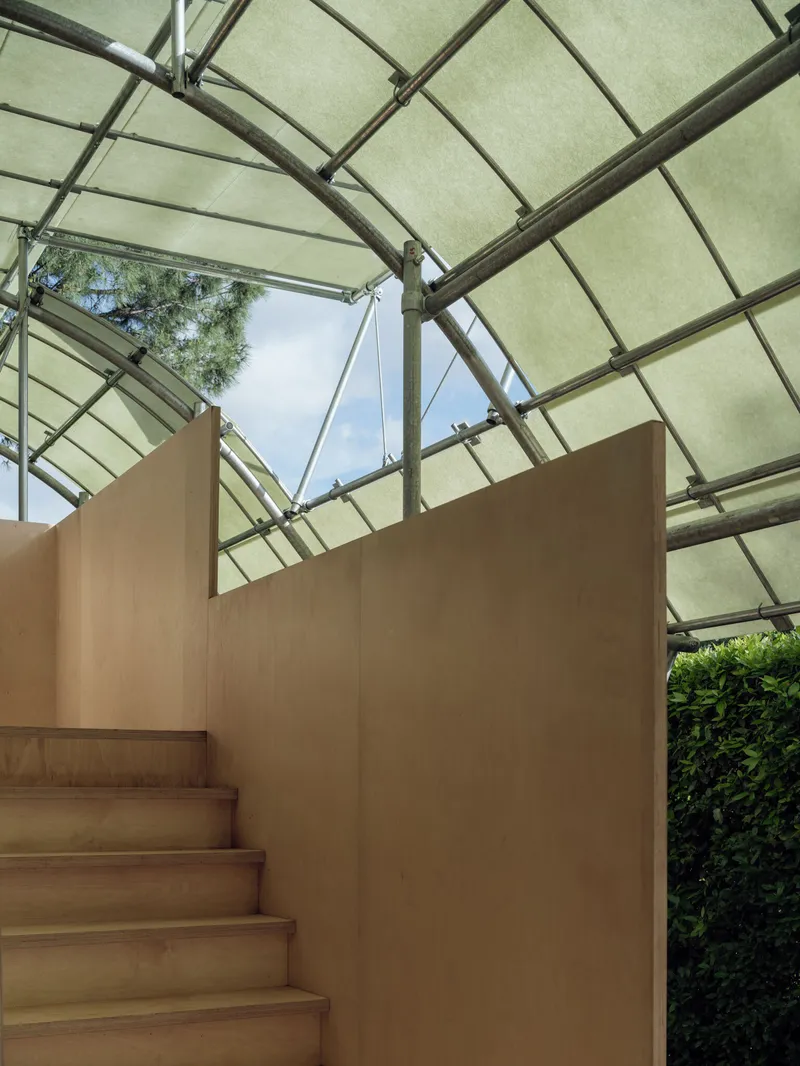 Timber staircase enclosed by plywood walls beneath the steel and fabric roof structure