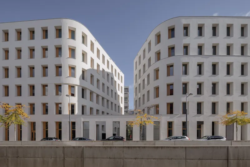 Courtyard view between two facades with identical window grids and parked cars at dusk