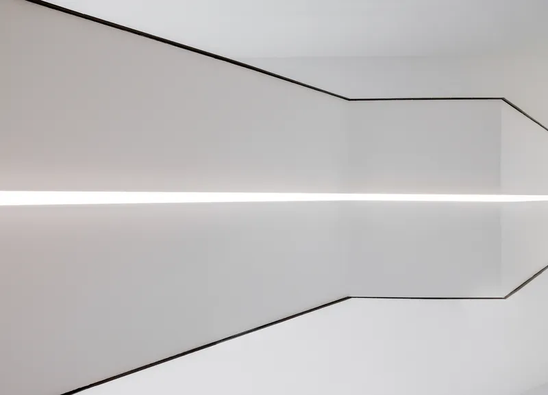 Close-up of a coved ceiling corner with continuous linear lighting and thin metal edge trim