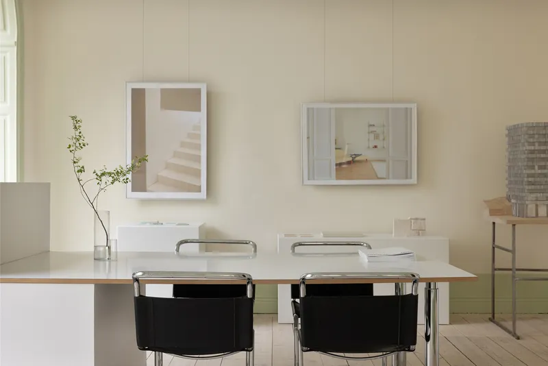 Workspace with table, framed photographs, and an architectural model on the right-hand shelf