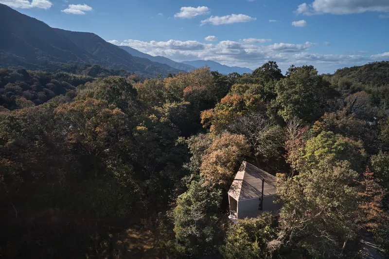 Aerial view of the small timber structure nestled among autumn foliage with mountains in the distance