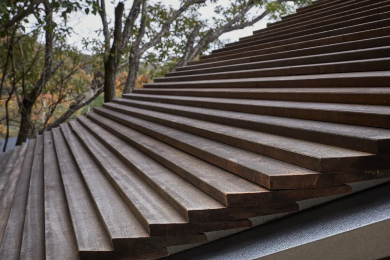 Close-up of horizontal timber slat facade with trees visible in the background