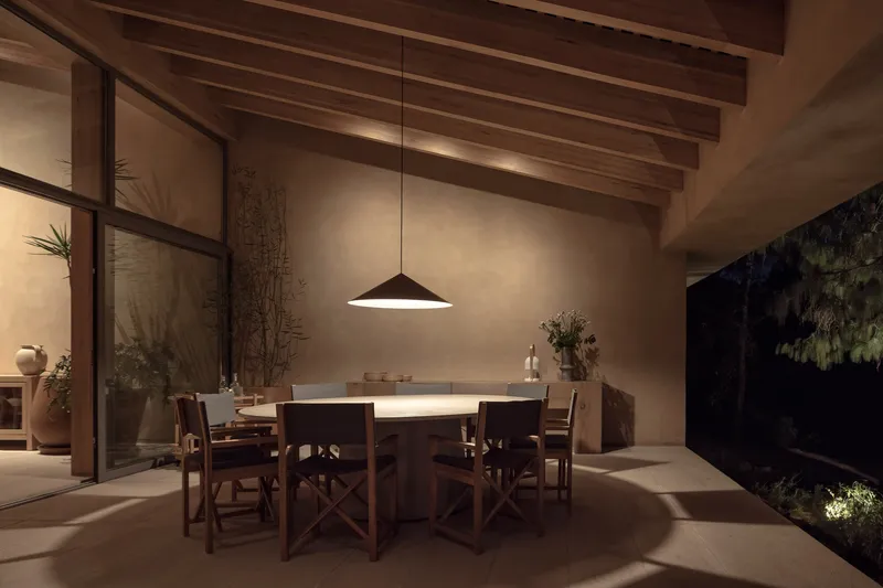 Dining area with exposed timber beams and conical pendant light illuminating the table at night
