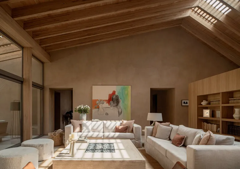 Vaulted ceiling with exposed timber rafters and slatted skylights illuminating a living area below