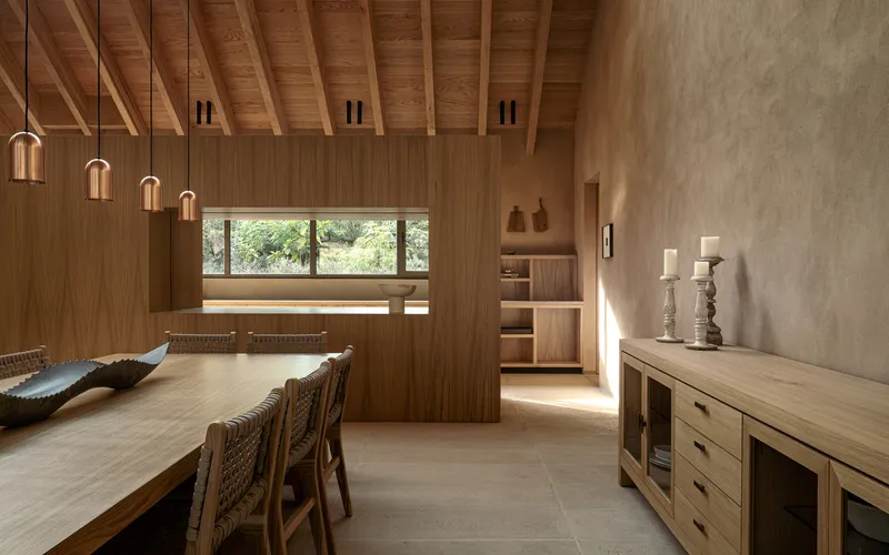 Timber-lined dining area with exposed ceiling joists and horizontal window framing distant trees