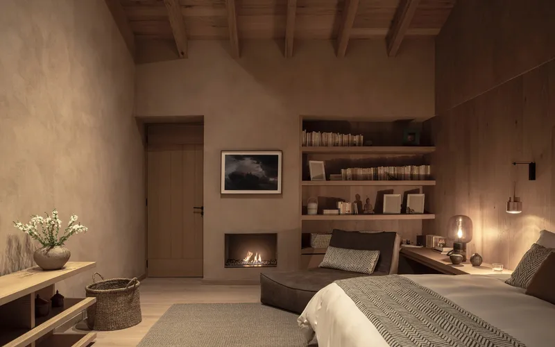 Bedroom view at dusk with fireplace flickering beside timber-clad wall and open shelving