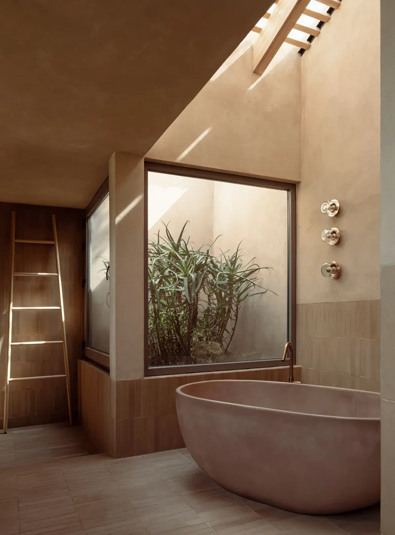 Freestanding bathtub beside a glazed courtyard planted with bamboo beneath a skylit ceiling