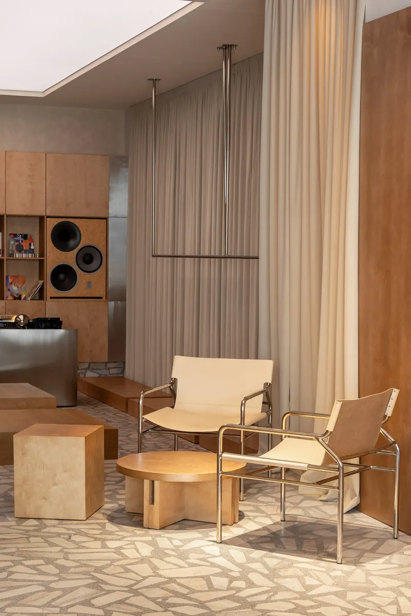 Seating area with canvas chairs and low timber table beside a suspended metal clothing rack