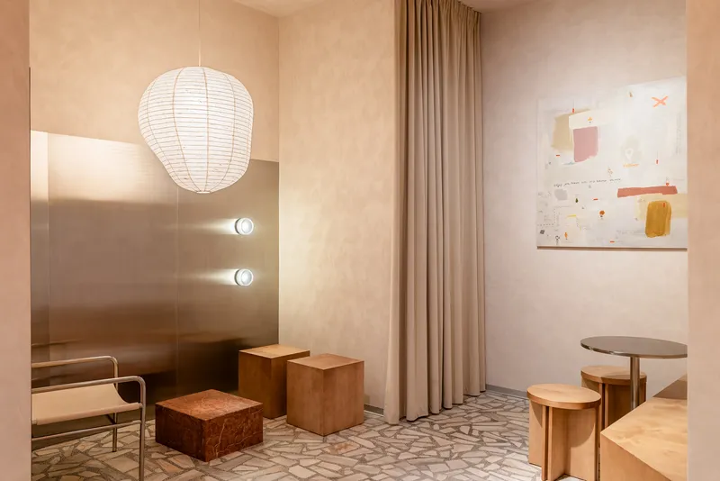 Corner alcove with paper lantern pendant light and abstract artwork above terrazzo flooring