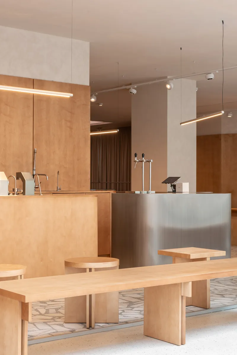 Interior counter area with light wood joinery and brushed metal surfaces under suspended track lighting
