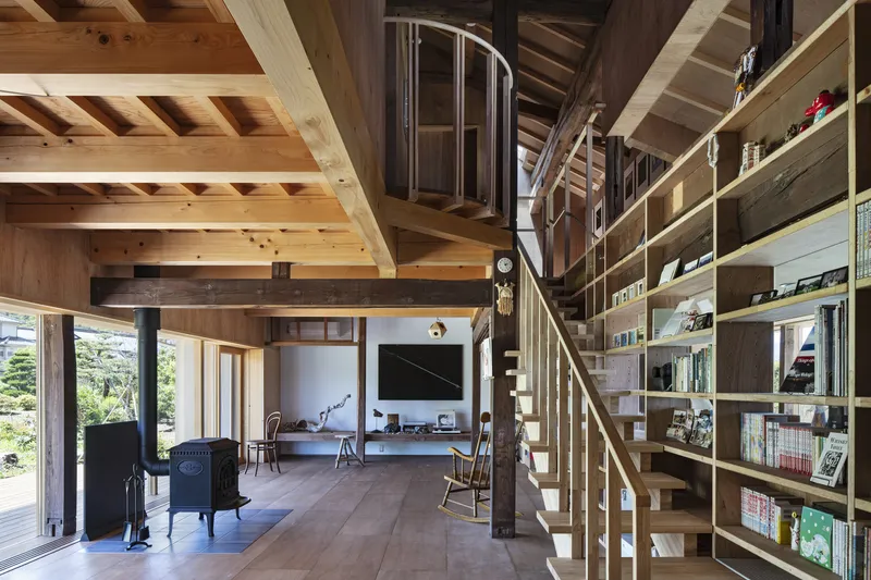 Double-height living space with spiral staircase flanked by floor-to-ceiling timber bookshelves