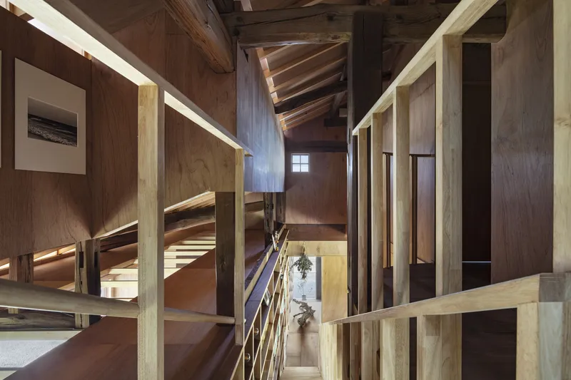 Upper floor landing with timber guardrails and sunlight streaming through small clerestory window
