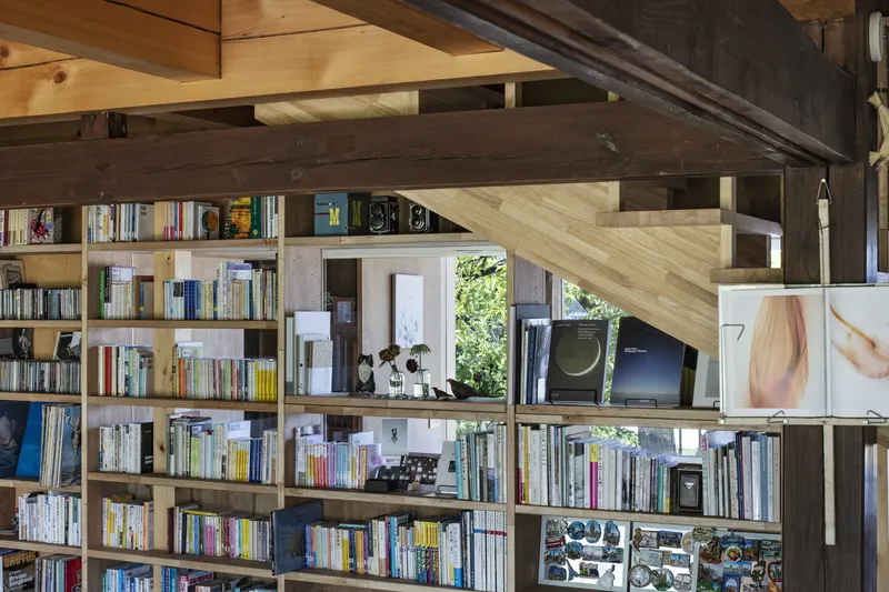 Interior view of timber-framed bookshelves beneath a pitched ceiling with exposed beams and diagonal bracing