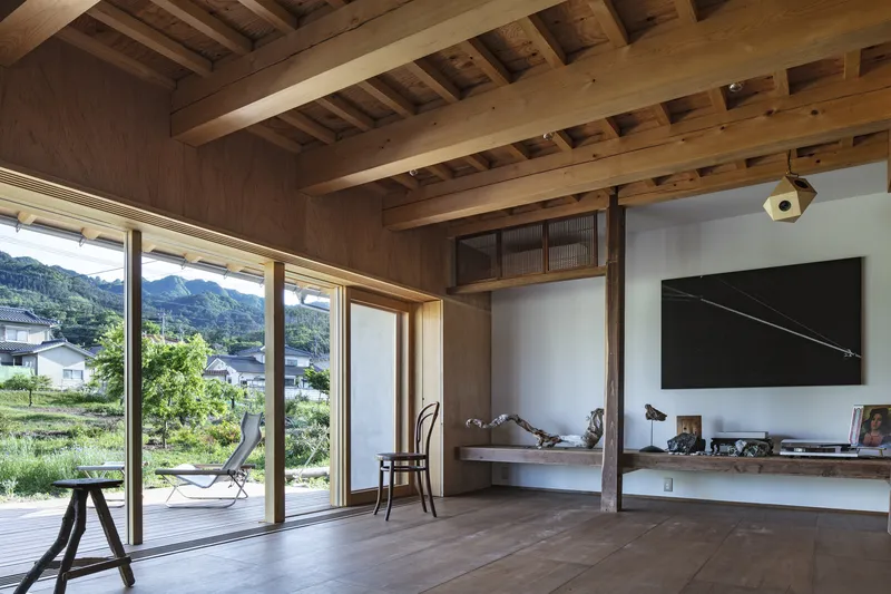 Living area with exposed timber beams and full-height glazing opening to green fields beyond