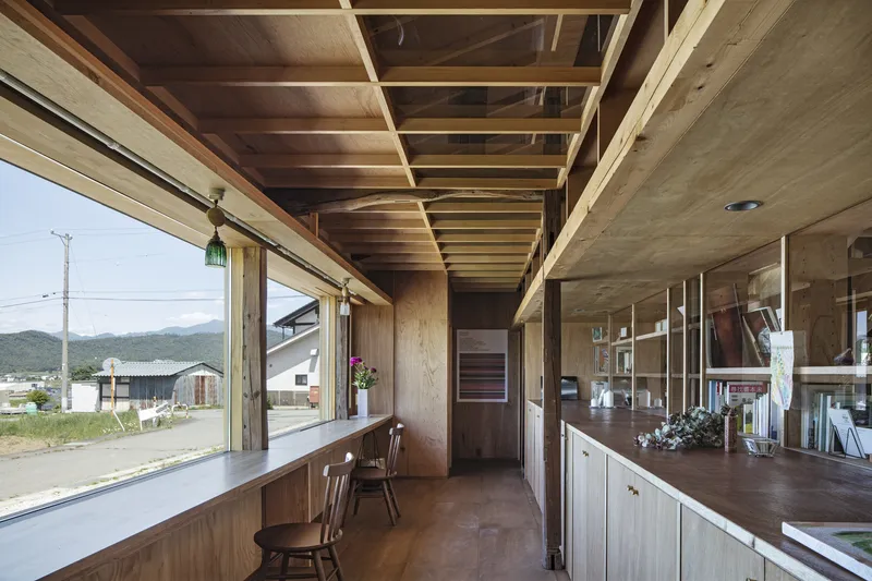 Interior workspace with exposed timber ceiling joists and sliding glass doors overlooking distant mountains