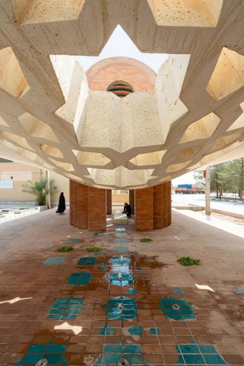 View through a star-shaped concrete canopy with timber screens and turquoise tile floor under bright daylight