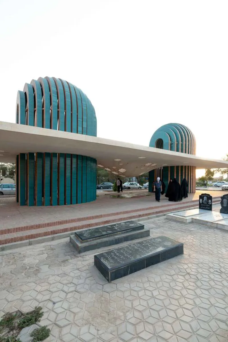 Exterior view showing turquoise ribbed domes rising from the horizontal roof plane at dusk near a parking area
